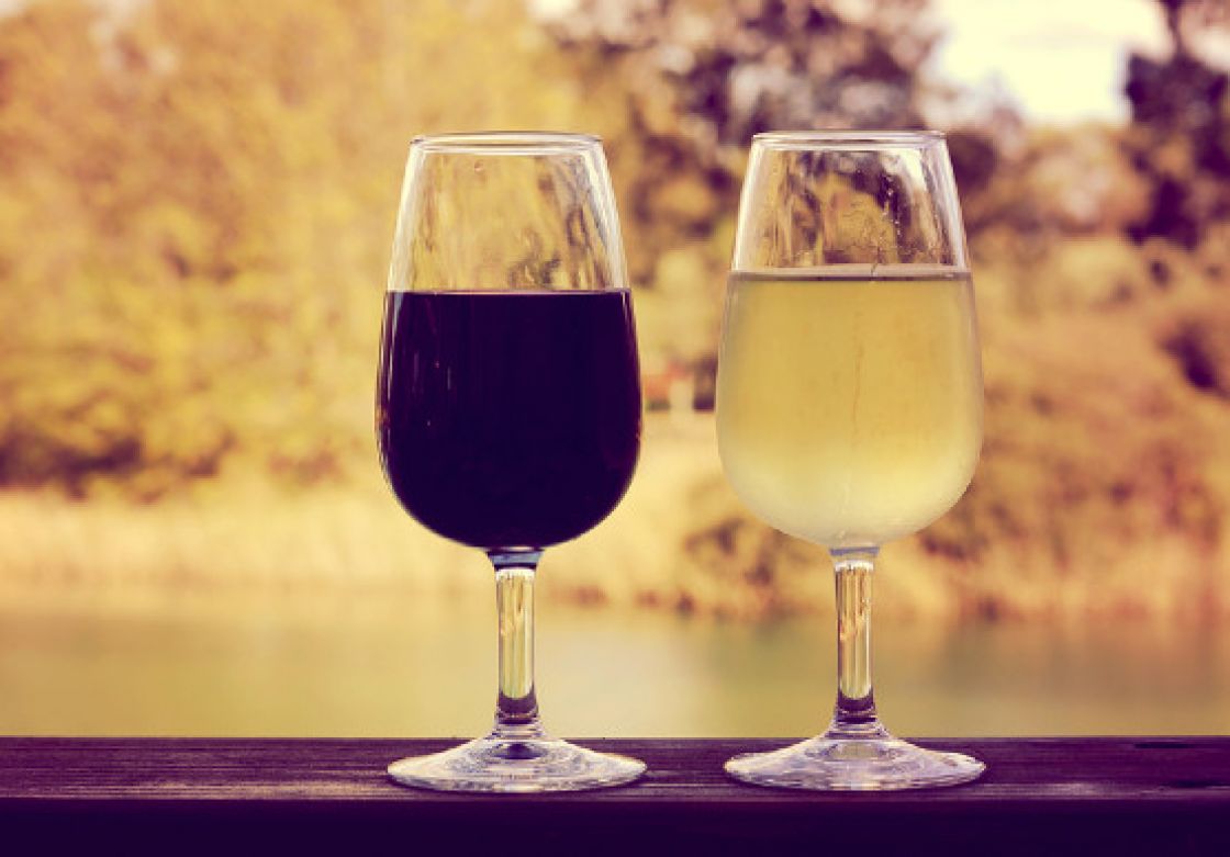 A glass of red wine on the left and a glass of white wine on the right.