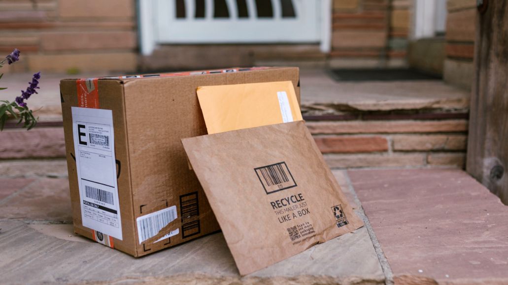 A box and 2 envelopes on a front porch.