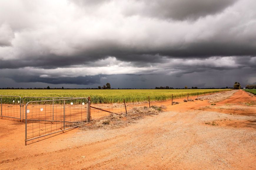 Farm gate and paddock with storm clouds passing through