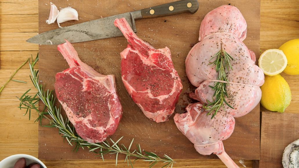Two cuts of beef and a roast sit on a kitchen cutting board