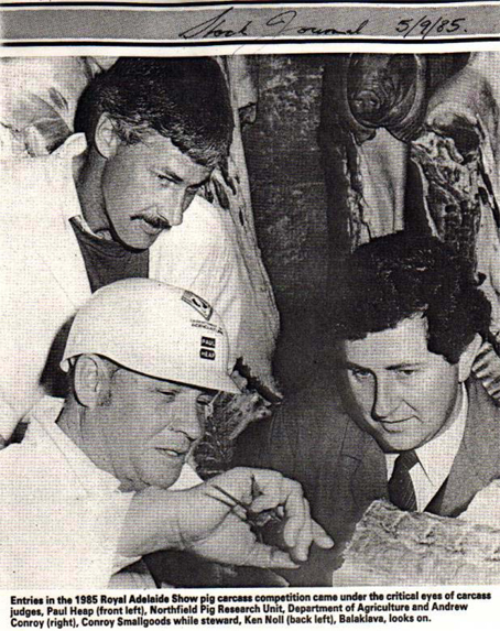 At the 1985, RAHS Bacon Carcass competition Judges Paul Heap and Andrew Conroy, measure and access the eye muscle of an entry. Ken Noll looks on.