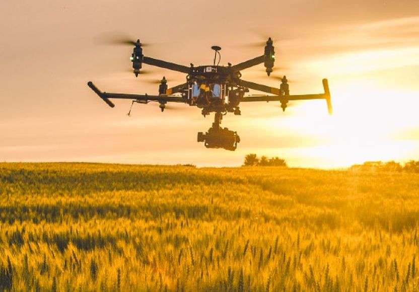 A drone with camera attached flying over crops