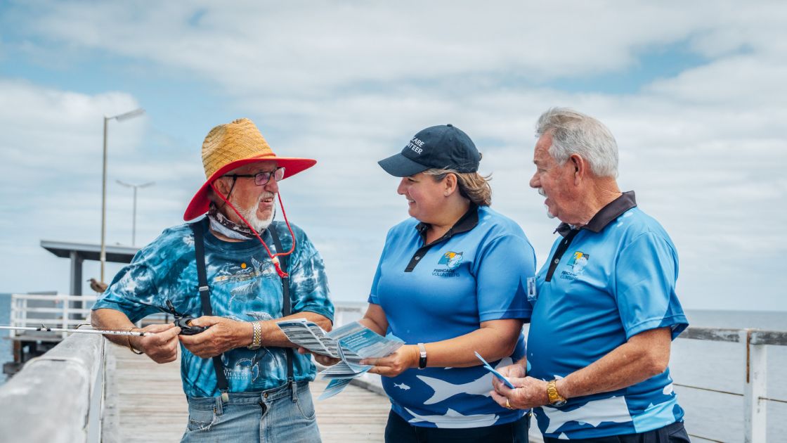 Two fishing volunteers talk to a local recreational fisherman